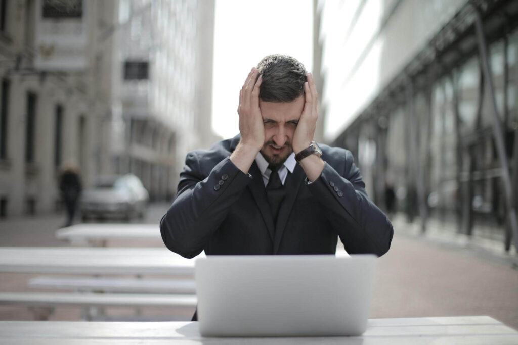 Man sitting in front of his laptop looking stressed. Don't use reminders in your to do list.