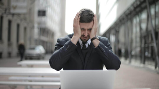 Man sitting in front of his laptop looking stressed. Don't use reminders in your to do list.