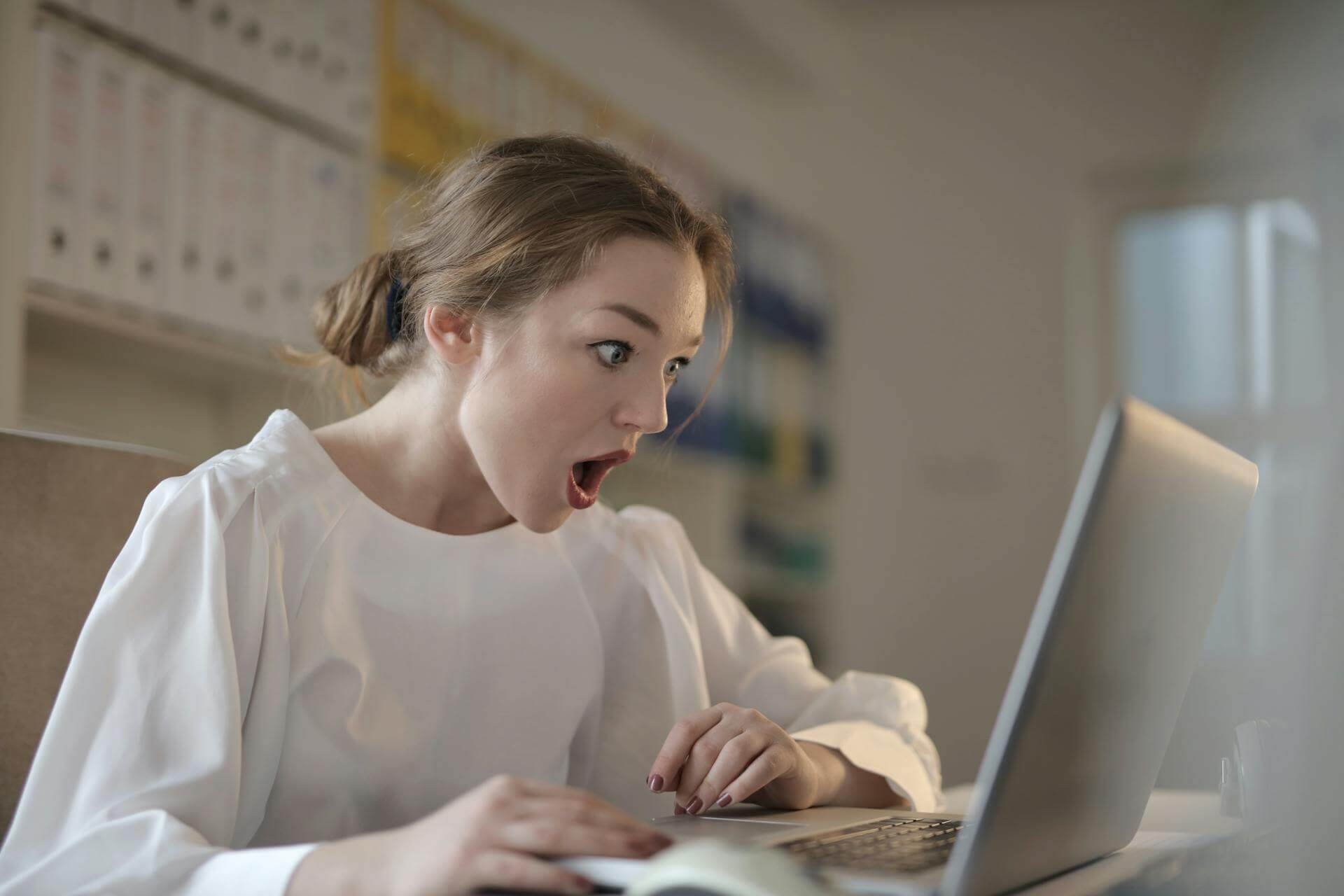 Surprised expression by a lady looking at her laptop because the recall this message feature in outlook worked!